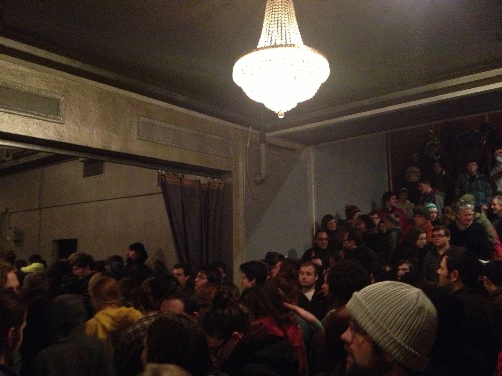 A packed crowd at Lupo's in Providence, crystal chandelier above, everyone shoulder to shoulder waiting for Jeff Mangum