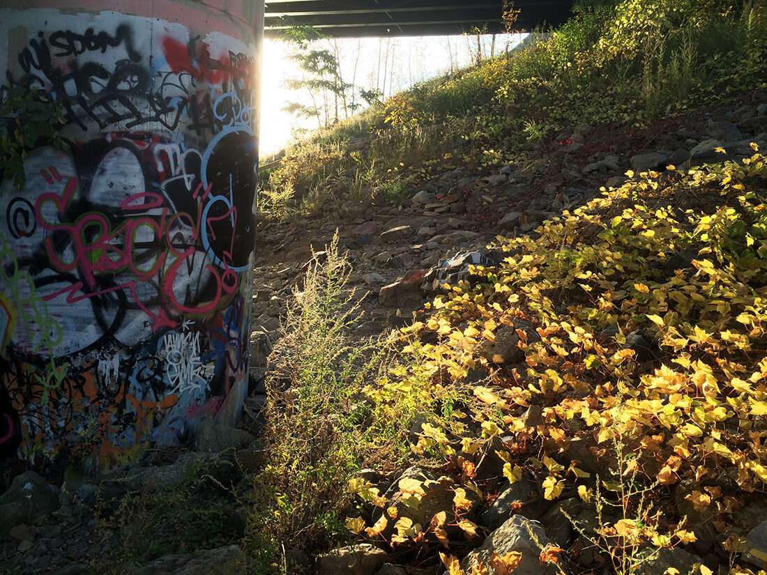  light peeking through a concrete column that's covered in graffiti