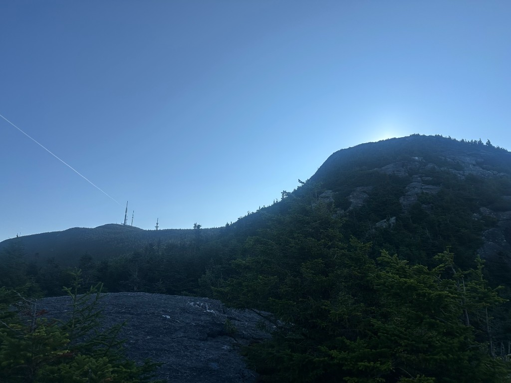 Morning silhouette of Mt. Mansfield ridge with radio towers and The Chin visible, sun rising behind