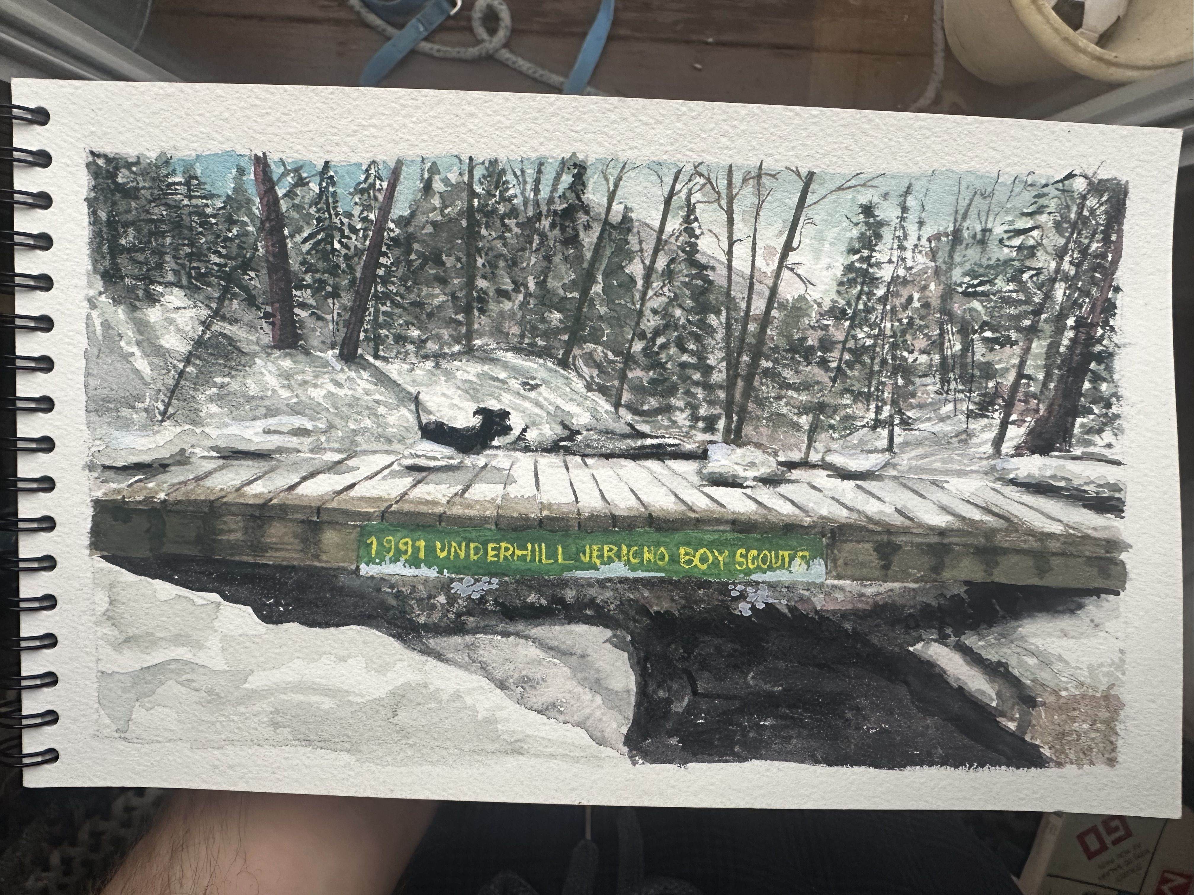 Watercolor painting of a winter scene with a river going under a bridge and a green sign on the bridge reading 1991 underhill Jericho, Boy Scouts, with a dog in the background playing in the water
